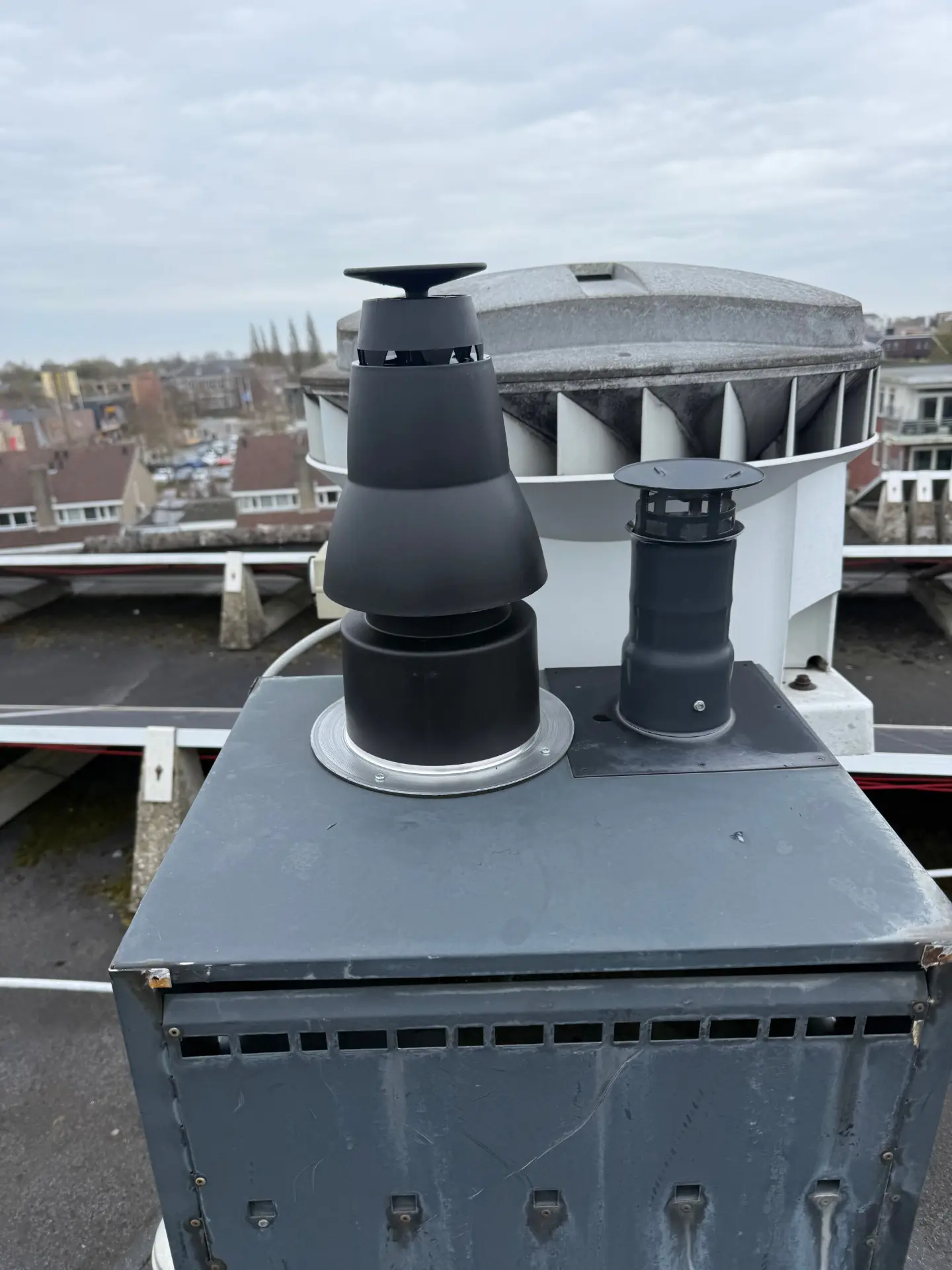 Zwarte dakdoorvoeren voor rookgasafvoer en luchttoevoer op een plat dak