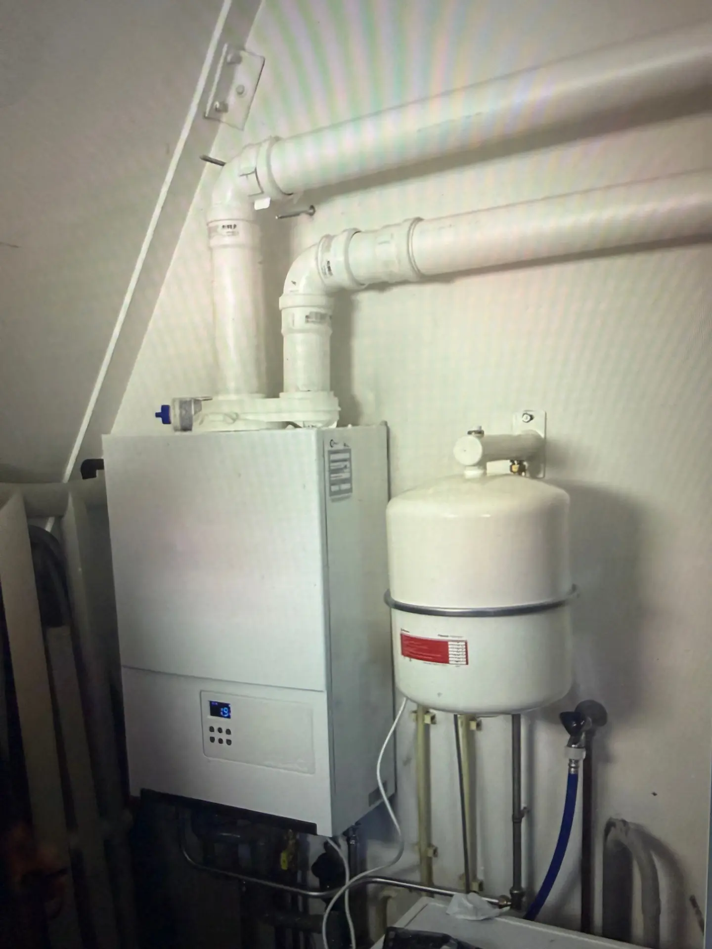 Cv-ketel met rookgasafvoer en expansievat onder een schuine wand