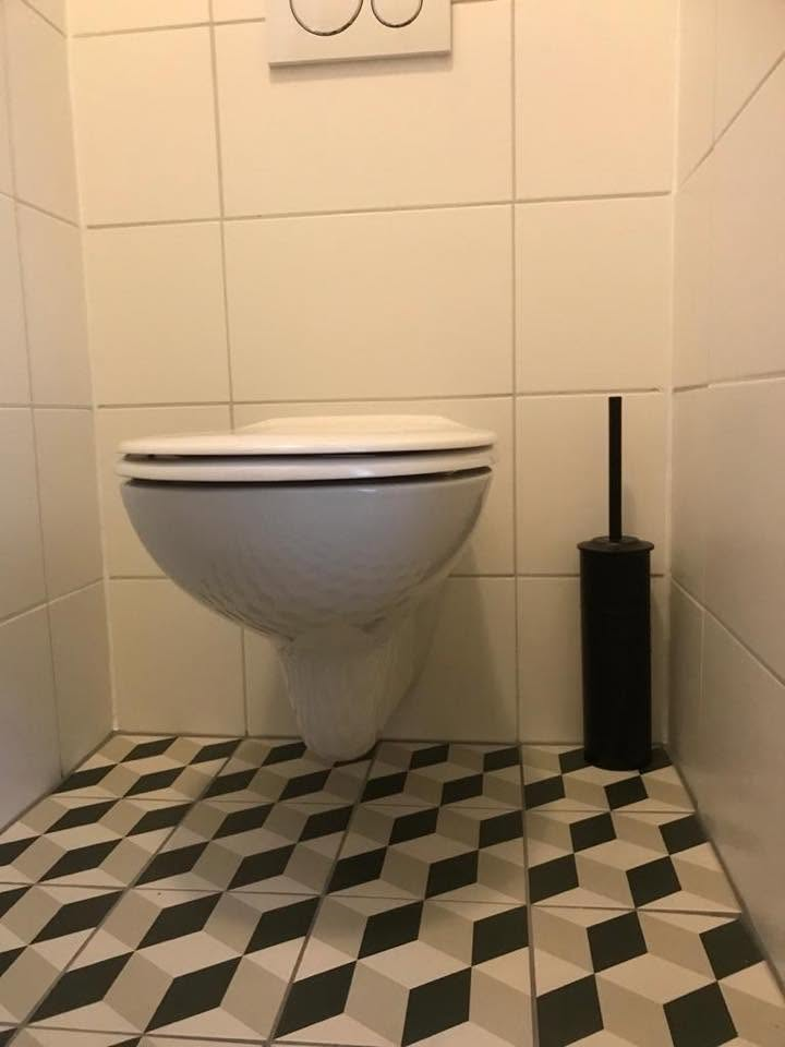 Hangend toilet boven een zwart-witte tegelvloer