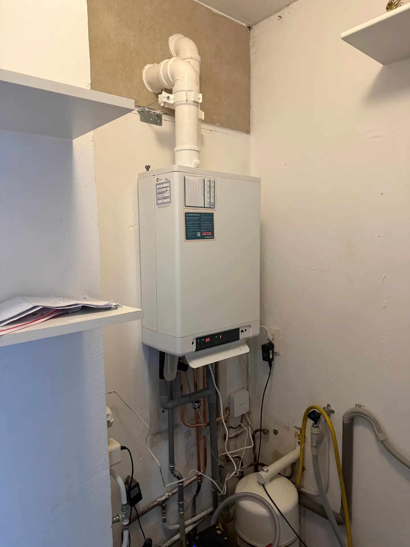 Nieuw opgehangen cv-ketel met leidingwerk in een technische ruimte